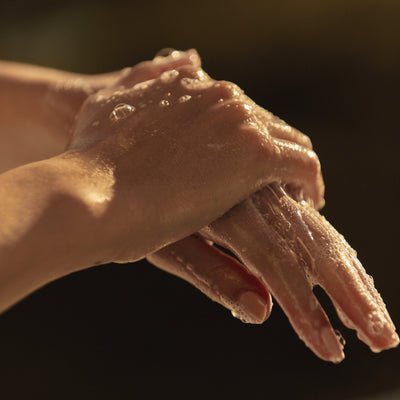 Close-up of hands washing with soap under running water